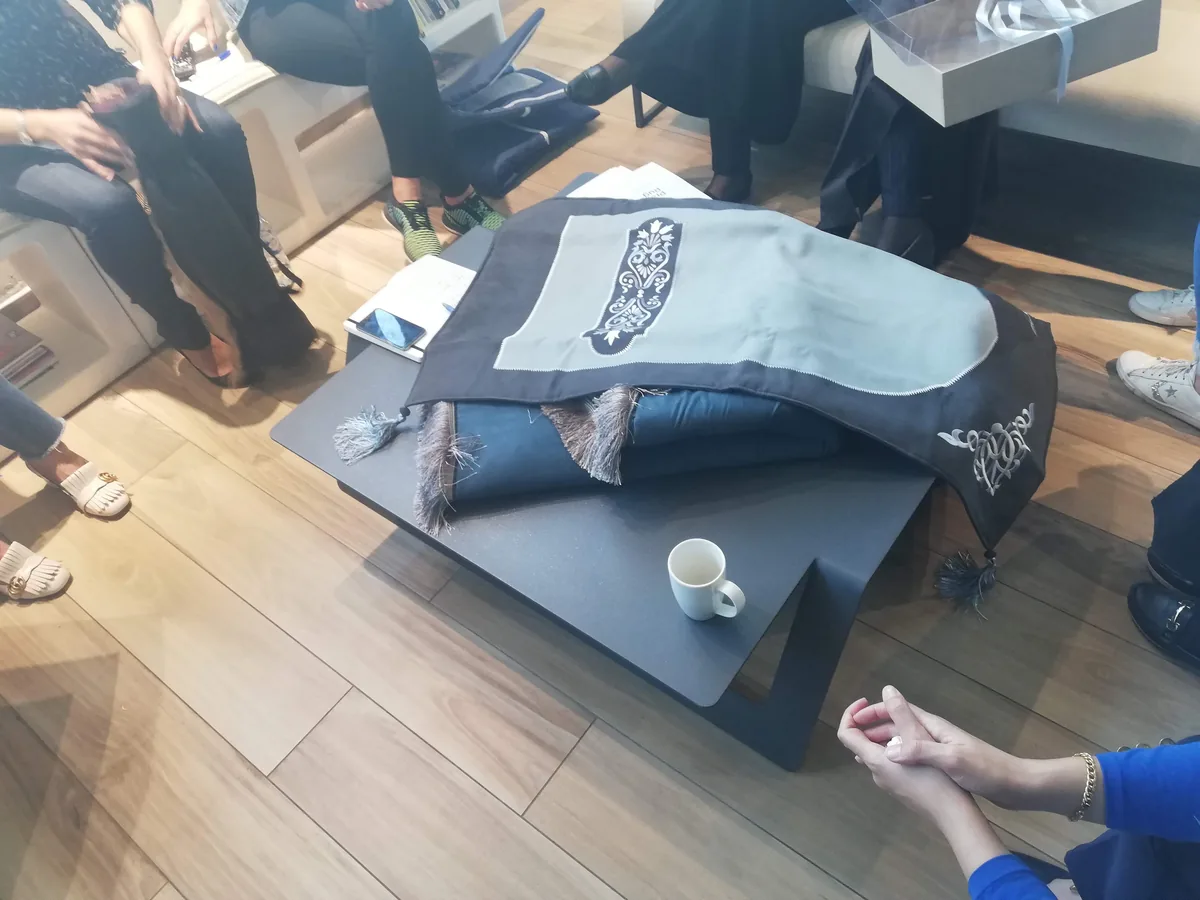 An embroidered prayer rug laid out for review during a design mentoring session