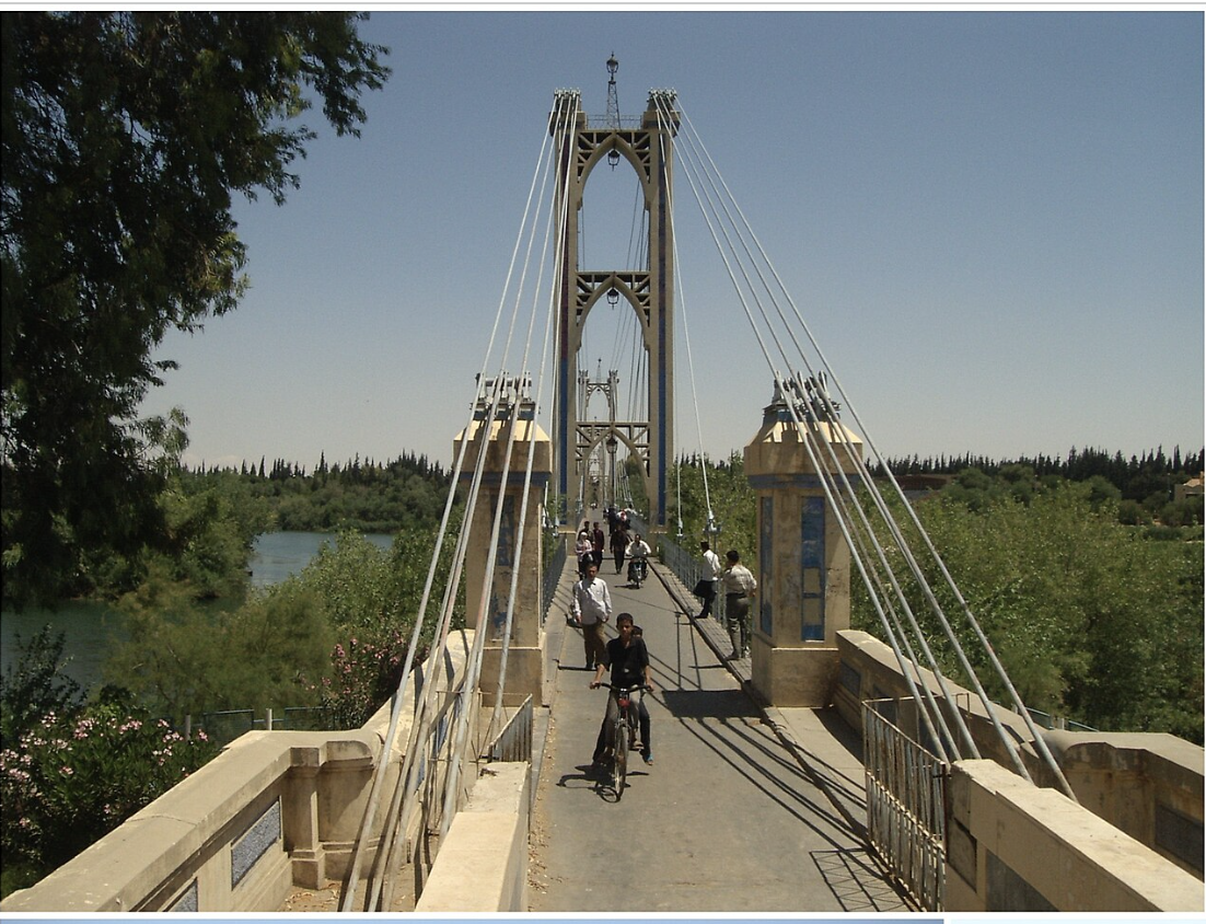Deir ez-Zor suspension bridge over the Euphrates, with pedestrians and cyclists crossing on a clear day